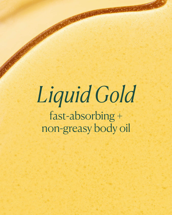 Close-up of a yellow body oil with 'Liquid Gold' text on a beige background