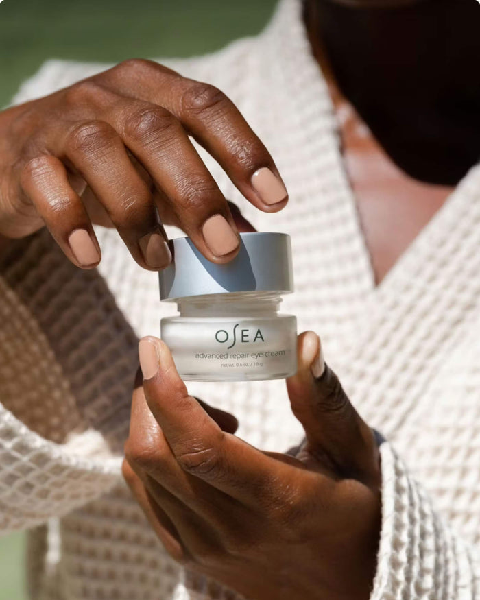 Person holding a OSEA skincare product with a blurred background