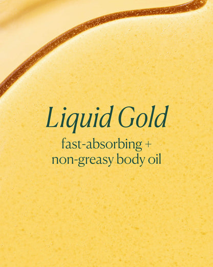 Close-up of a yellow body oil with 'Liquid Gold' text on a beige background