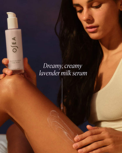 Woman applying Ojea lavender milk serum to her arm with a dark background