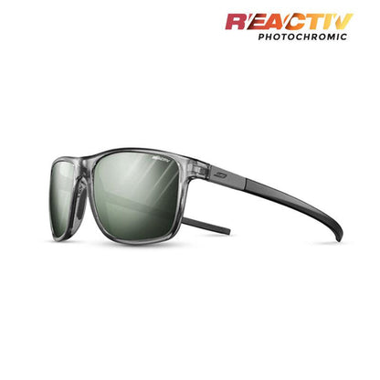 The Streets sunglasses by Julbo Eyewear feature a gray frame, green lenses, and black arms, shown at an angle. The ergonomic design ensures all-day comfort. "REACTIV Photochromic" text appears in the top right corner. #color_black-gray-with-reactiv-1-3-glare-control-lens