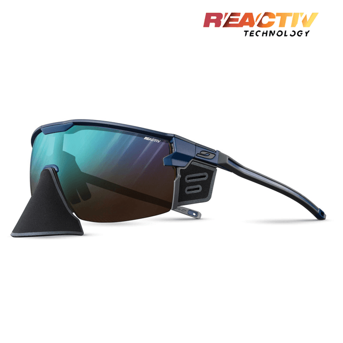 The Julbo-usa Ultimate Cover sports sunglasses feature blue frames, side shields, REACTIV Technology branding, and a panoramic lens for top sun protection—ideal mountain eyewear. #color_blue-with-reactiv-2-4-lens