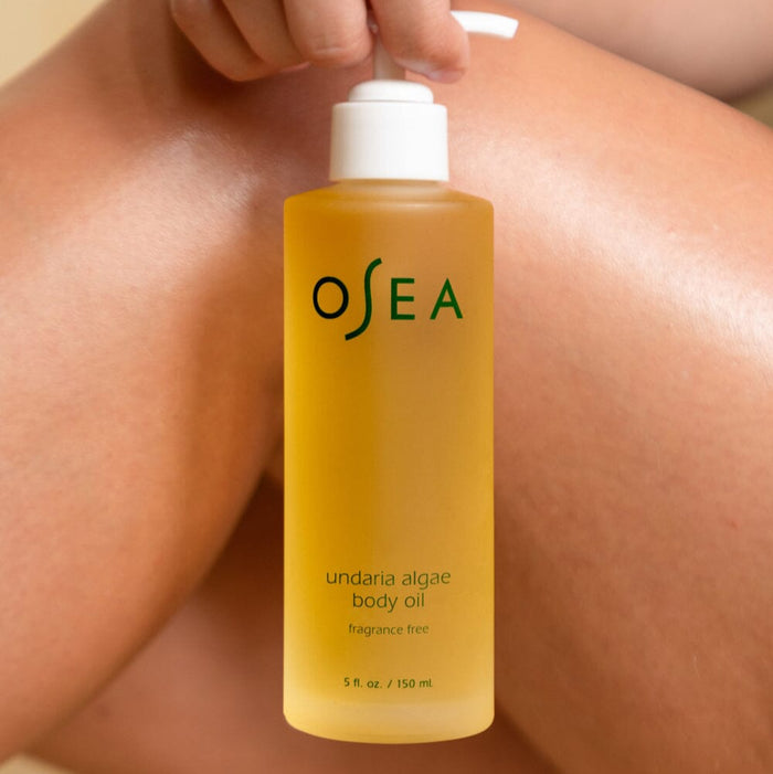 Undaria Algae Body Oil Fragrance-Free bottle held against skin to highlight gentle, sensitive-skin formula