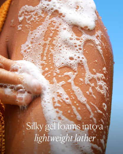 Person applying foamy gel to their skin with a blue background