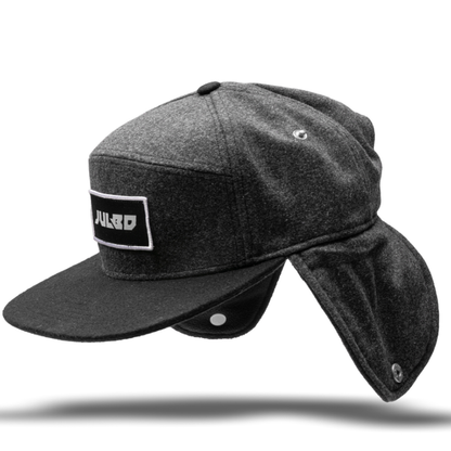 Keep warm in cold weather with the Julbo Eyewear Woodsman Hat—this dark gray hat has a black brim, long ear and neck flaps, and a JULBO logo patch on the front. #color_julbo-woodsman-hat-charcoal